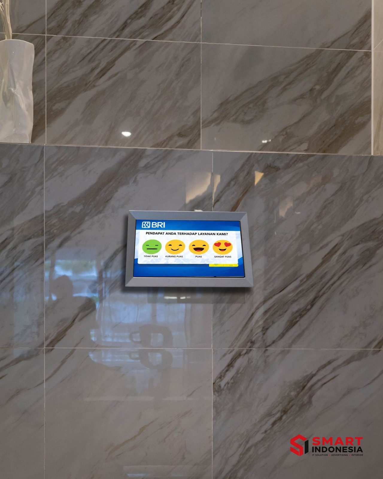 Instalasi SmartSanitasi — Unit survei kepuasan SmartSanitasi terpasang di dinding marmer — BRI